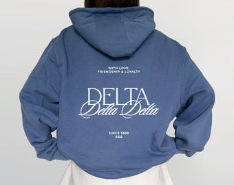 Może przedstawiać: Niebieska bluza z kapturem z białym napisem na plecach o treści WITH LOVE, FRIENDSHIP & LOYALTY, DELTA, Delta Delta oraz SINCE 1888 AAA. Bluza posiada kaptur, długie rękawy i jest zestawiona z gładkimi białymi szortami.
