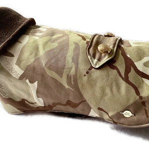 Op de afbeelding: Camouflage hondenjas met een bruine fleecevoering en een gouden knoop. De jas heeft een bruin en beige camouflagepatroon.