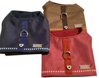 May include: Three dog harnesses in navy blue, brown, and burgundy. Each harness has a D-ring, a decorative strap, and a small metal tag. The navy blue harness has a blue strap with a diamond-shaped accent. The burgundy and brown harnesses have heart-shaped accents.
