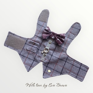 May include: A grey plaid dog vest with a brown bow tie and a gold chain. The vest has a pocket on the front and velcro closures on the straps. "With love by Evie Beavie" is written on the bottom of the image.