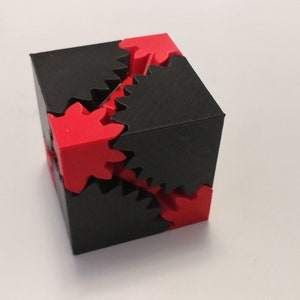 Könnte beinhalten: Ein schwarz-roter 3D-gedruckter Würfel mit ineinandergreifenden Zahnrädern auf jeder Seite.