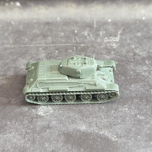 以下が含まれることがあります： 詳細なデザインの、オリーブグリーンの小さなおもちゃの戦車。戦車には砲塔、キャタピラ、その他のリアルな要素があります。おもちゃはおそらくプラスチック製で、遊びや展示用に設計されています。