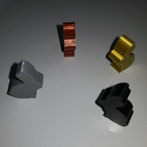 Può includere: Quattro piccole figurine di coniglio in diversi colori: grigio, marrone, oro e nero. Le figurine sono in plastica e hanno una finitura liscia e lucida.