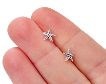 Peut inclure: Une paire de boucles d'oreilles en forme d'étoile de mer en argent. Les boucles d'oreilles sont petites et délicates, et elles seraient un excellent cadeau pour quelqu'un qui aime l'océan.