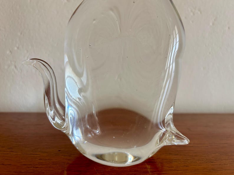May include: A clear glass pitcher with a curved spout and a rounded body. The pitcher is made of transparent glass, allowing light to pass through. The design is simple and elegant, suitable for serving beverages.