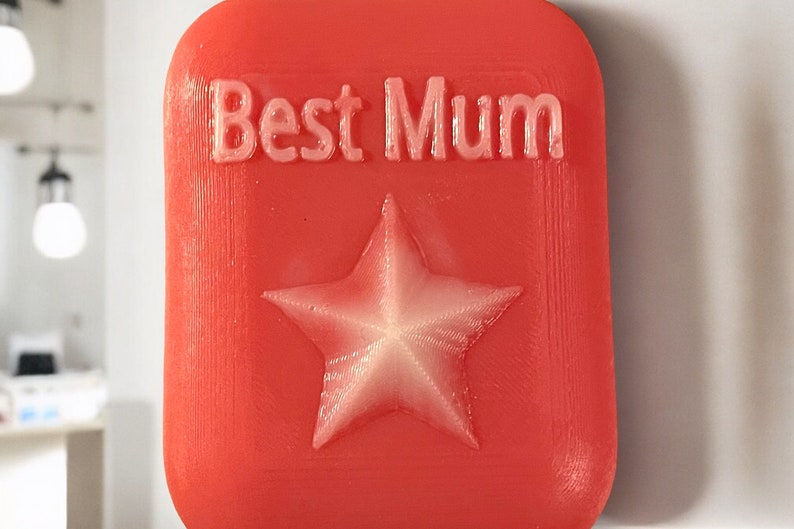 May include: A red square-shaped plaque with the words "Best Mum" in white lettering and a white five-pointed star in the centre.