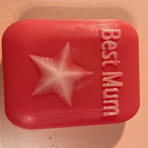 May include: A pink square-shaped soap with a white star and the text "Best Mum" embossed on the front.