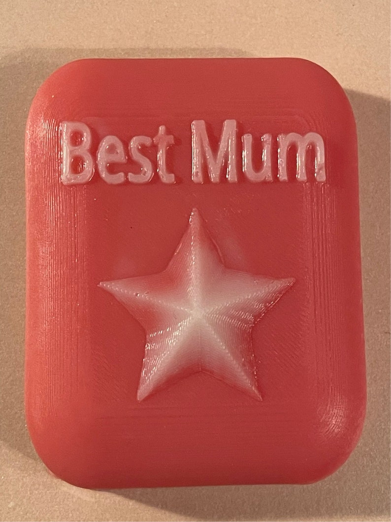 May include: A red rectangular soap bar with the words "Best Mum" embossed in white and a white star in the centre.