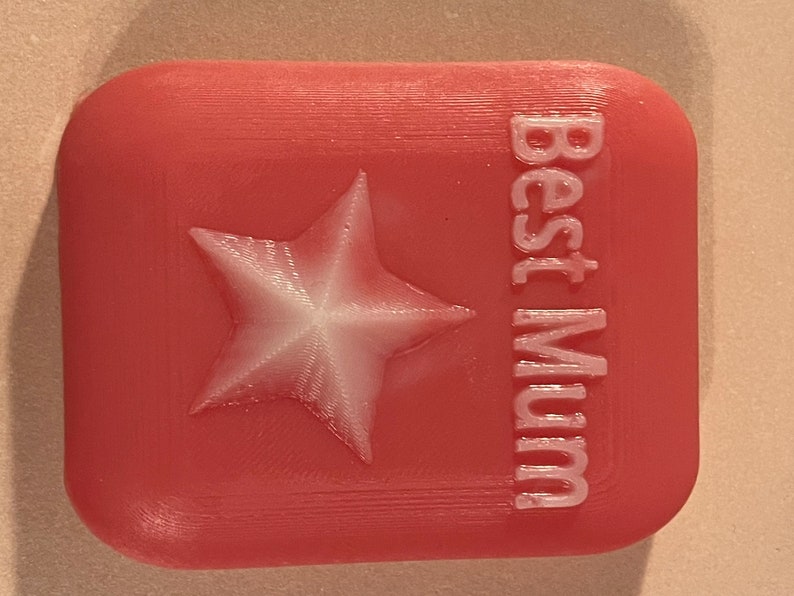 May include: A pink 3D printed box with a white star and the text "Best Mum" on the front.