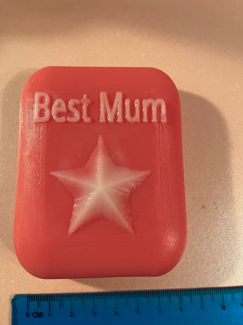 May include: A pink rectangular soap with the words "Best Mum" embossed in white and a white star in the centre.
