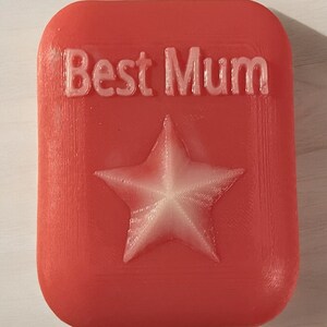 May include: A red rectangular soap with the words "Best Mum" embossed in white and a white five-pointed star in the centre.