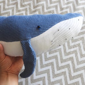 Peut inclure: Une peluche baleine bleue avec un ventre blanc et des coutures d&eacute;taill&eacute;es. La baleine a une texture en velours c&ocirc;tel&eacute; et un petit &oelig;il noir. Le jouet est con&ccedil;u pour ressembler &agrave; une baleine et convient aux enfants.