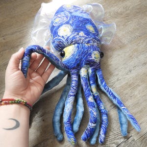 Puede incluir: Un peluche de pulpo con un dise&ntilde;o de tela azul inspirado en "La noche estrellada" de Van Gogh. El juguete tiene ojos amarillos, tent&aacute;culos azules y un cuello transparente con volantes. Un peluche &uacute;nico y art&iacute;stico.