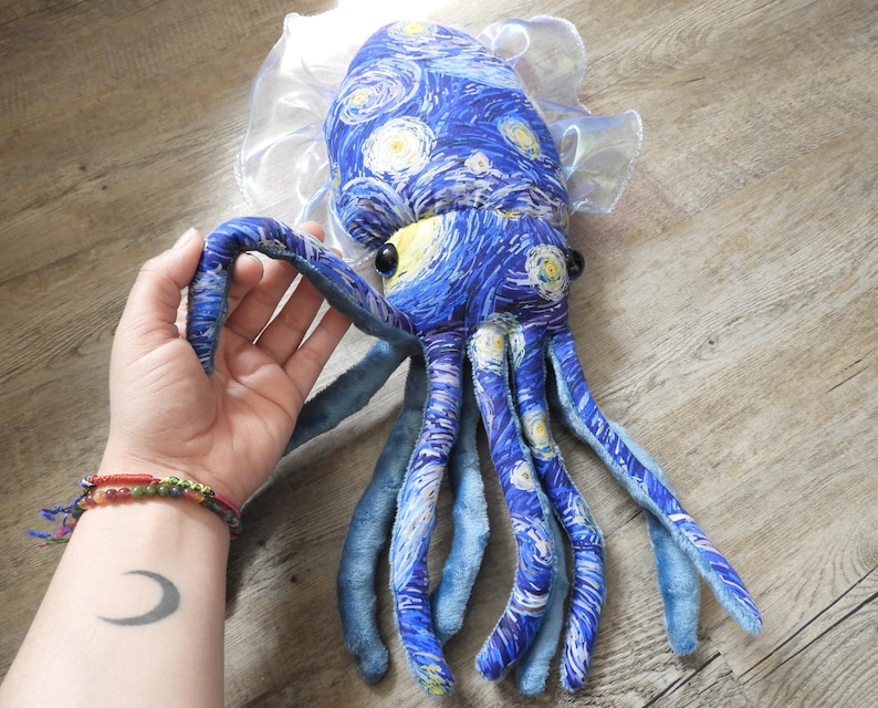 Puede incluir: Un peluche de pulpo con un dise&ntilde;o de tela azul inspirado en "La noche estrellada" de Van Gogh. El juguete tiene ojos amarillos, tent&aacute;culos azules y un cuello transparente con volantes. Un peluche &uacute;nico y art&iacute;stico.