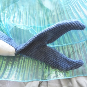 Peut inclure: Un jouet en forme de baleine bleue en peluche avec un ventre blanc et une texture en velours c&ocirc;tel&eacute;. La queue de la baleine est incurv&eacute;e et pos&eacute;e sur un tissu bleu iris&eacute; et chatoyant. Le jouet est con&ccedil;u pour ressembler &agrave; une baleine.