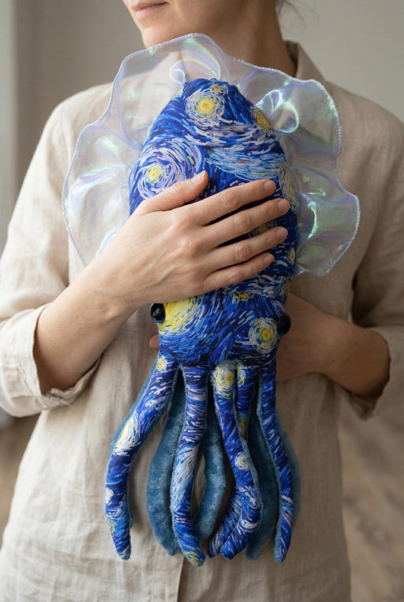 Puede incluir: Un peluche de pulpo con el cuadro "La noche estrellada" de Van Gogh. El dise&ntilde;o azul y amarillo cubre el cuerpo y los tent&aacute;culos. El juguete tiene un cuello con volantes e iridiscente.
