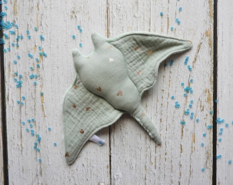 May include: A light green stuffed manta ray with gold glitter hearts. The manta ray is made of soft fabric and has a long tail.