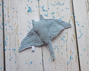 May include: A light blue and white spotted fabric manta ray stuffed animal toy. The toy has a white tag with the word "Oce" on it.