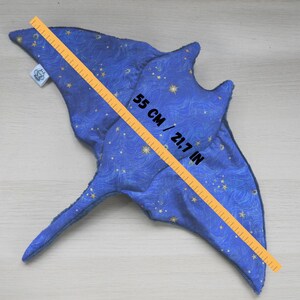 K&ouml;nnte beinhalten: Ein blaues Pl&uuml;schtier in Form eines Mantarochens mit Sternenmuster und einer Gr&ouml;&szlig;e von 55 cm. Das Spielzeug besteht aus weichem Stoff und hat ein detailliertes Design, einschlie&szlig;lich Flossen und Schwanz. Das Spielzeug ist 55 cm lang.