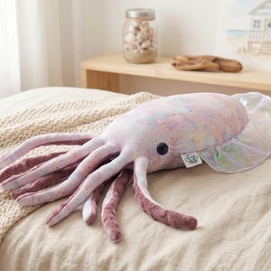 May include: A plush squid toy in pastel colors, with long, soft tentacles in shades of pink and purple. The body is a mix of pink, blue, and yellow, with a pearlescent fin. A cute, whimsical ocean-themed plush toy.