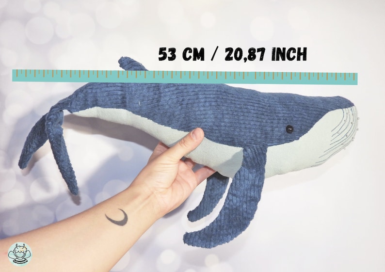 Peut inclure: Une peluche baleine bleue de 53 cm de long, avec un ventre et des nageoires bleu clair. La baleine est faite d'un tissu textur&eacute;, de type velours c&ocirc;tel&eacute;, et a un petit &oelig;il noir. Le jouet est pr&eacute;sent&eacute; sur fond blanc.