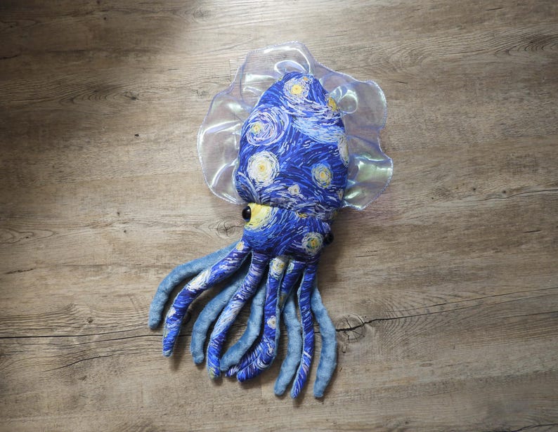 Puede incluir: Un juguete de peluche con forma de calamar con un dise&ntilde;o de noche estrellada azul y amarillo. El calamar tiene tent&aacute;culos azules y una pieza para la cabeza transparente y con volantes. El juguete est&aacute; hecho de tela suave y est&aacute; dise&ntilde;ado para parecerse a la famosa pintura.