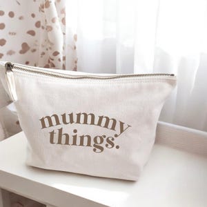 May include: A white canvas zippered pouch with the text "mummy things." printed in brown.
