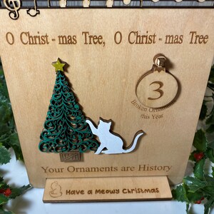 Puede incluir: Un adorno de árbol de Navidad de madera con un gato blanco, un árbol de Navidad verde y una estrella dorada. El adorno dice "O Christmas Tree, O Christmas Tree" y "Your Ornaments are History". La base del adorno dice "Have a Meowy Christmas".