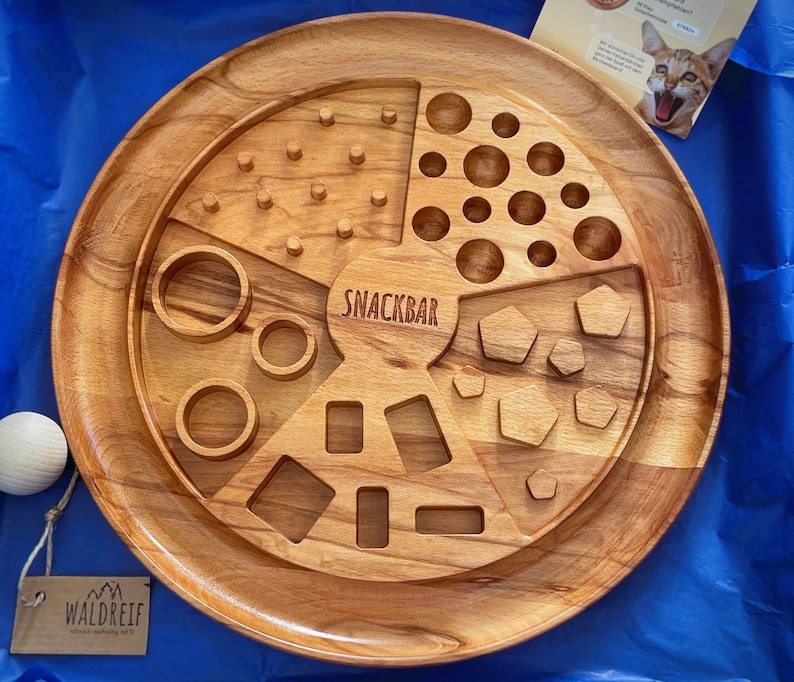 May include: A wooden snack board with various compartments for snacks. The board is divided into five sections, each with a different design. The center section features the word "Snack Bar".