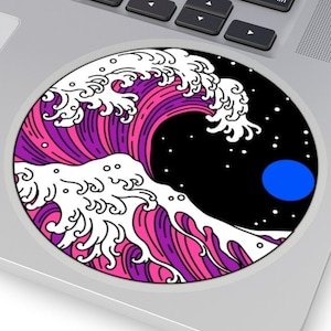 May include: A round sticker featuring a stylized wave design in shades of pink, purple, and white, set against a black background with a blue circle and white stars. The sticker is placed on a laptop.