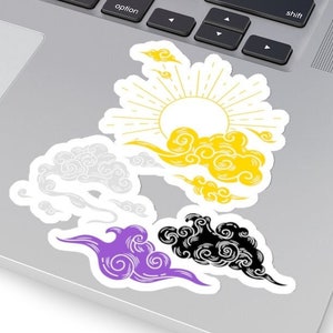 May include: A set of five stickers featuring stylized clouds in yellow, white, purple, and black. The clouds are arranged in a semi-circle with a sun in the center. The sun has yellow rays and a white circle in the center.
