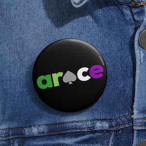 May include: A black button with the word "ar ace" written in green, white, and purple letters. A spade symbol is in the center of the word "ace".