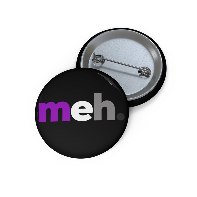 May include: A black button with the word "meh" in purple, white, and gray letters. The button has a silver pin on the back.