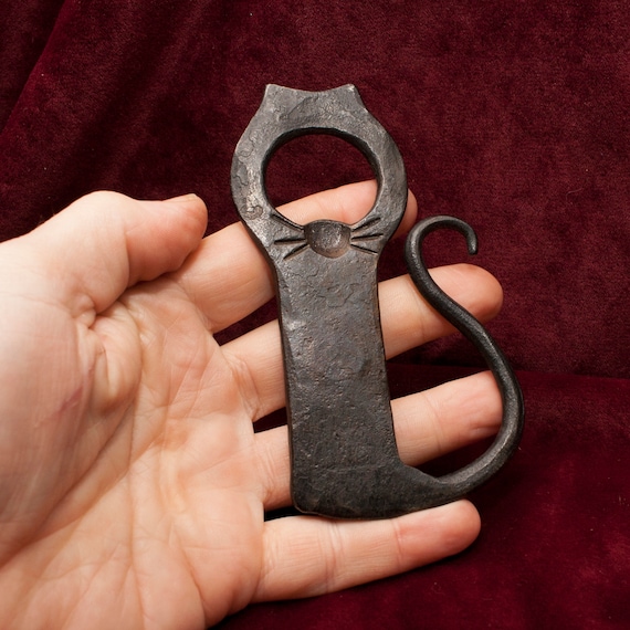 A blacksmith shaped the steel into actual cat whiskers — functional art that doubles as a conversation-starting gift for cat-loving beer drinkers.