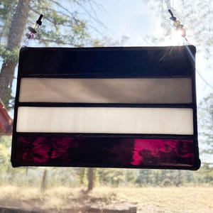 Peut inclure: Une fenêtre en vitrail suspendue avec un motif rayé noir, gris, blanc et violet.