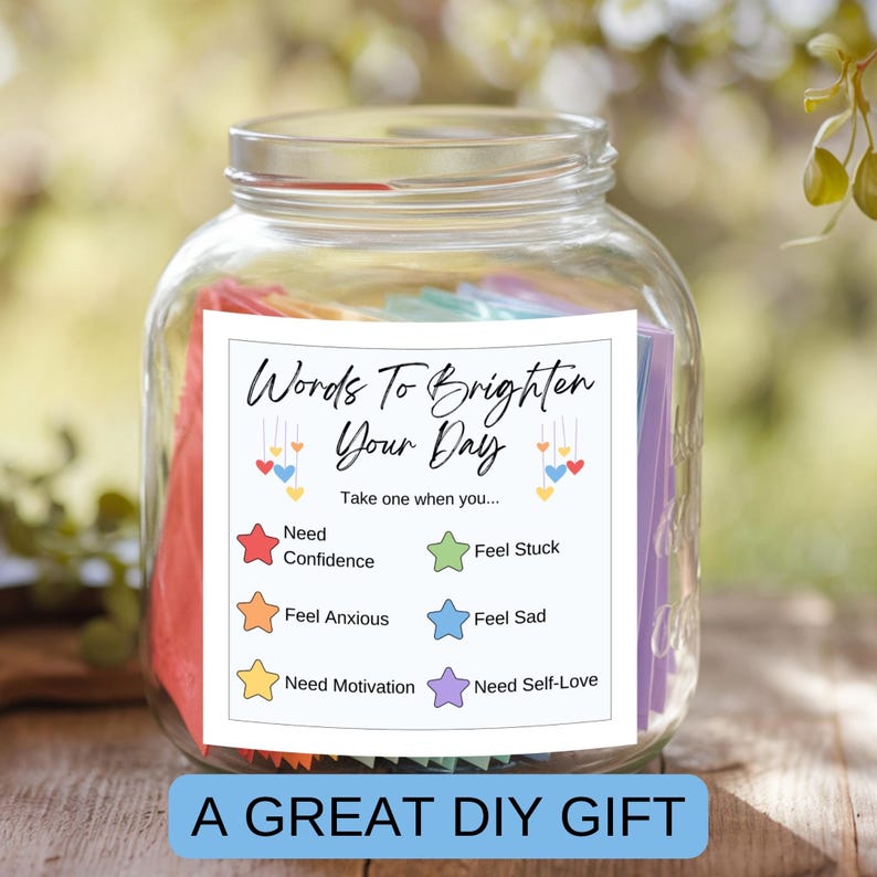 May include: A glass jar filled with colorful paper slips, each with words to brighten your day. The jar has a white label with the text "Words To Brighten Your Day" and instructions to "Take one when you..." followed by a list of feelings and needs, each with a corresponding colored star.