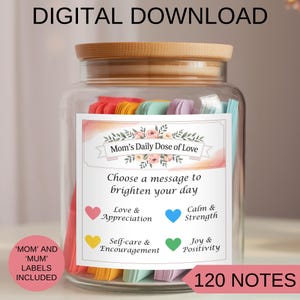 Puede incluir: Un tarro de vidrio con tapa de madera lleno de notas de papel de colores. El tarro tiene una etiqueta que dice "Mom's Daily Dose of Love" e incluye un mensaje para alegrar tu día. La etiqueta también incluye cuatro categorías de notas: Amor y Apreciación, Calma y Fuerza, Autocuidado y Aliento, y Alegría y Positividad. El tarro contiene 120 notas.