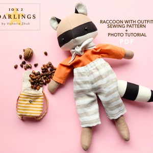 Op de afbeelding: Een naaipatroon voor een wasbeerpop met een oranje shirt en een gestreepte broek. Het patroon bevat een fototutorial en is beschikbaar als PDF-download. De tekst "10 X 2 DARLINGS by Victoria Zhuk" staat in de linkerbovenhoek van de afbeelding.