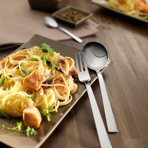 Könnte beinhalten: Ein Teller Spaghetti mit Lachs, Frühlingszwiebeln und Petersilie, serviert mit einer silbernen Gabel und einem Löffel.