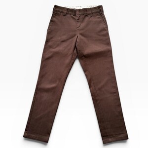 May include: A pair of solid brown trousers featuring a structured waistband with belt loops, a front zipper fly, and two side pockets. The pants have a straight-leg cut and a clean, flat-front design with visible stitching along the seams and hem.