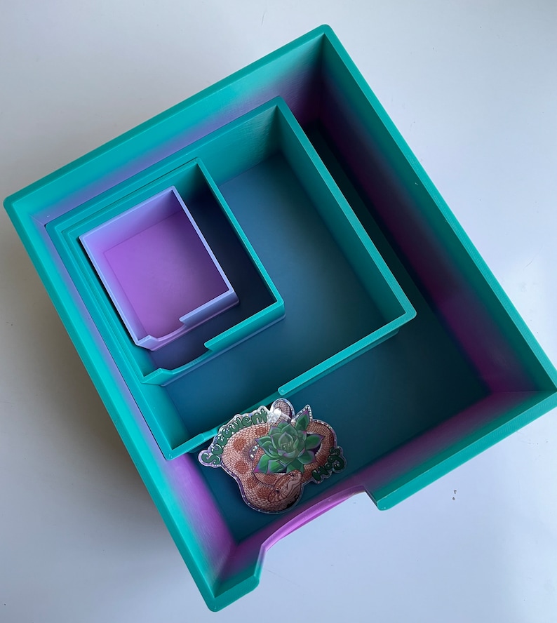 Op de afbeelding: Een set van drie in elkaar passende trays in een verloop van turquoise en paars. De grootste tray heeft een sticker aan de voorkant met de tekst "Succulent Queen".