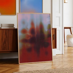 May include: Three framed abstract art prints with warm color gradients. The prints are displayed in a room with a wooden cabinet, a white lamp, and a modern chair. The room has a natural, minimalist aesthetic.