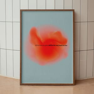 May include: A framed art print featuring a soft, abstract design in shades of orange and red against a light blue background. The print includes the text "all the love you give will find its way back to you". The frame is a dark brown color.