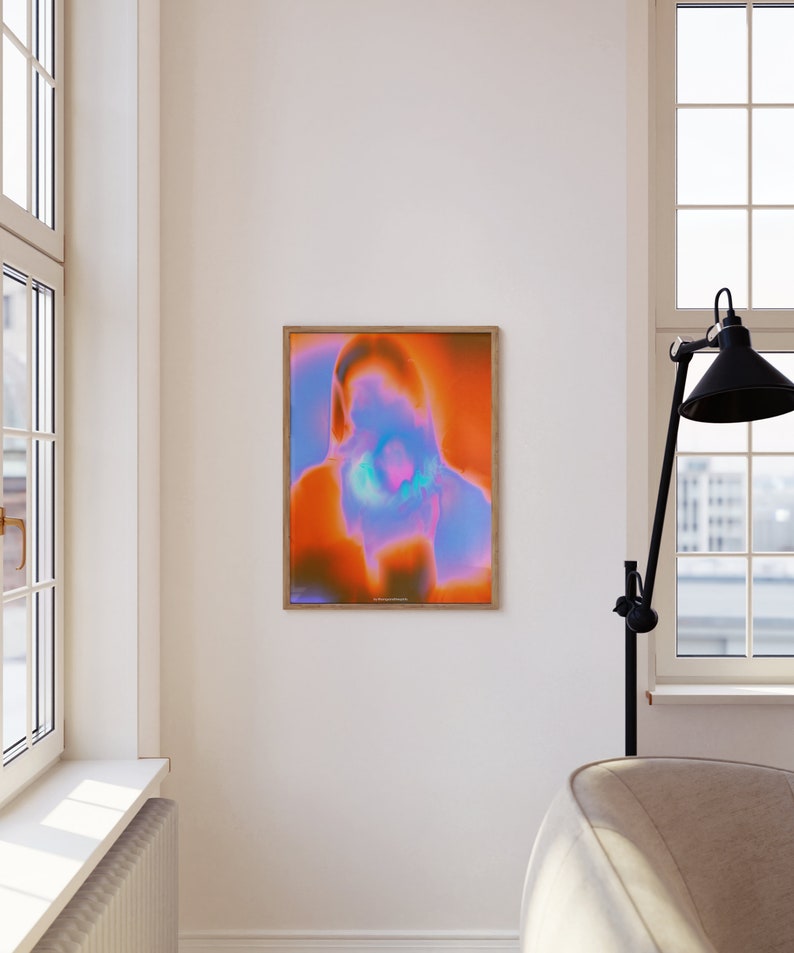 May include: Abstract art print with a vibrant orange, pink, and blue color scheme. The print is framed in a light wood frame.