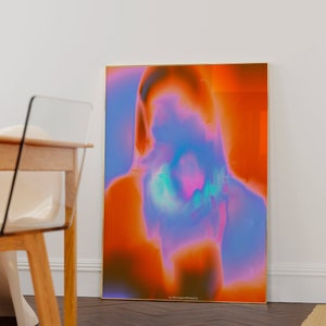 May include: Abstract art print with a blurred, colorful image of a person's face. The background is a gradient of orange, pink, and blue. The print is framed in gold and has the text "by @bangontheprints" at the bottom.