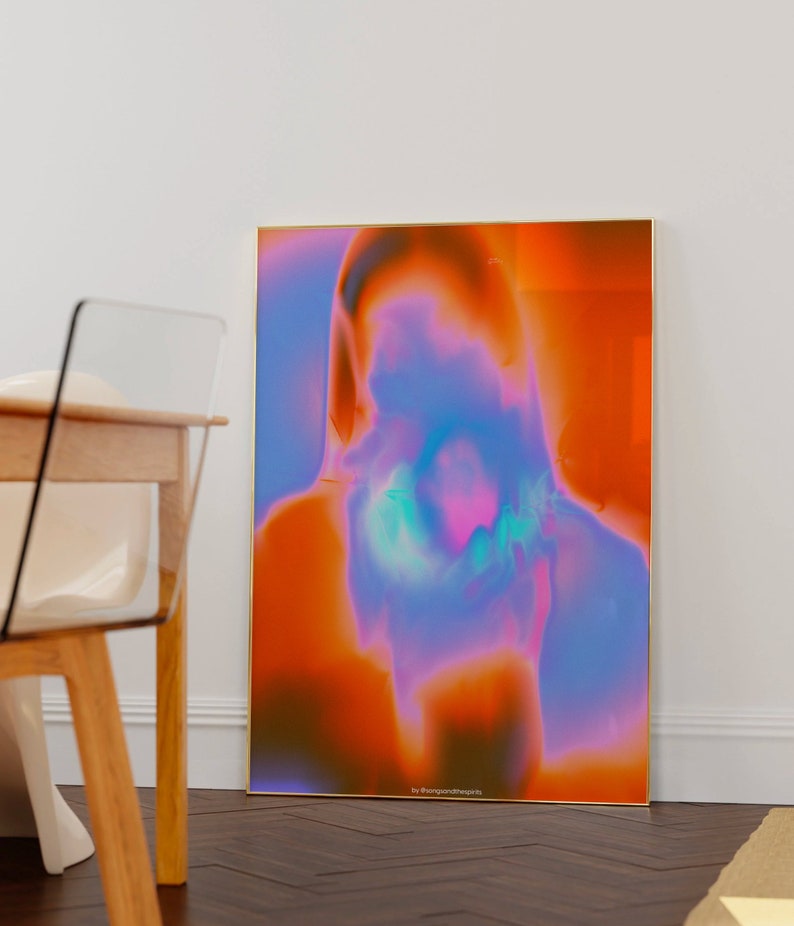 May include: Abstract art print with a blurred, colorful image of a person's face. The background is a gradient of orange, pink, and blue. The print is framed in gold and has the text "by @bangontheprints" at the bottom.