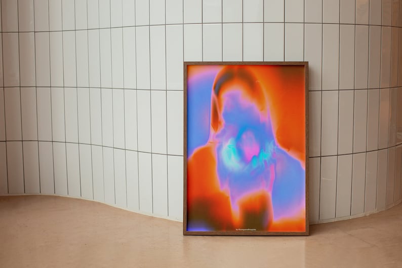 May include: A framed abstract print with a blurred image of a person's face in shades of orange, pink, and blue.