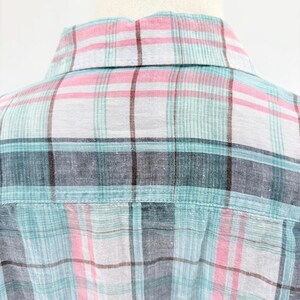 May include: Close-up of a plaid shirt collar and back yoke. The fabric features a pattern of intersecting lines in shades of pink, teal, gray, and brown on a white background. The shirt is made of a lightweight material.