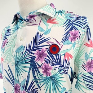 May include: White polo shirt with a tropical floral design in blue, purple, pink, and green. The shirt has a red and blue circular emblem on the chest and a classic collar.