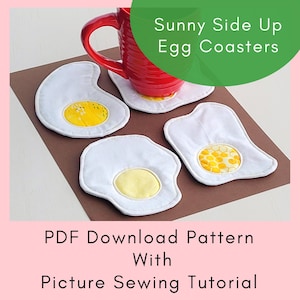 Puede incluir: Cuatro posavasos de tela blanca con forma de huevos fritos con centros de tela amarilla. Los posavasos están sobre una superficie marrón con una taza roja encima de uno de los posavasos. El texto "Sunny Side Up Egg Coasters" está en texto verde sobre fondo blanco. El texto "PDF Download Pattern With Picture Sewing Tutorial" está debajo de los posavasos.